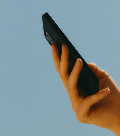 A hand with a mobile phone against a blue background.